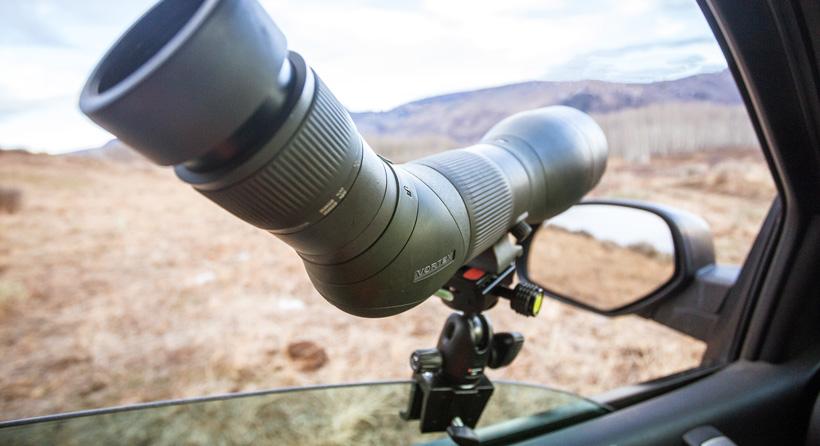 Summer mule deer scouting with spotting scope from a truck