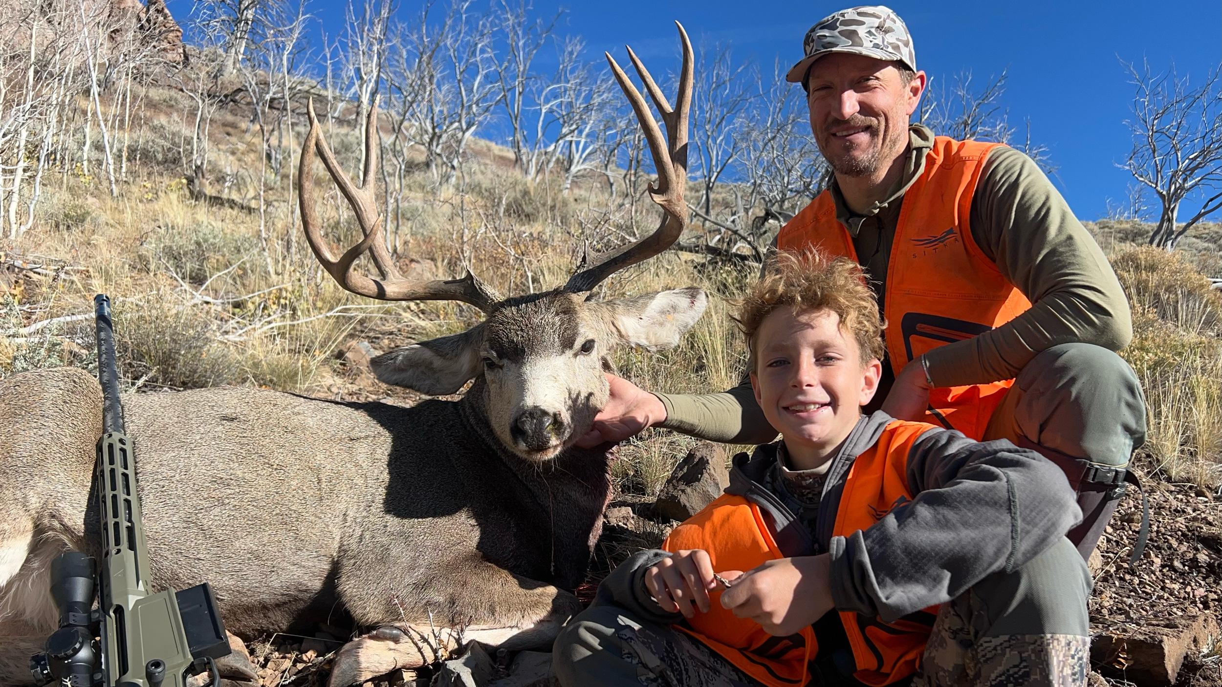 Trail Kreitzer and his son with a mule deer buck