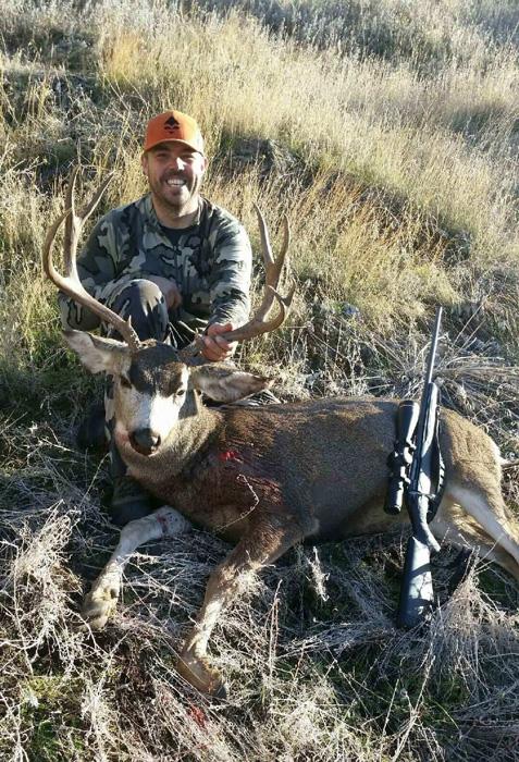 Hunter posing with their harvested mule deer
