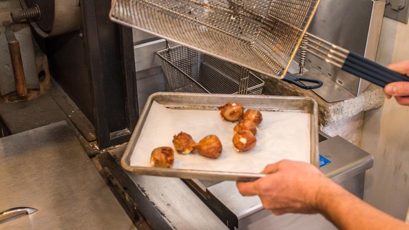 Removing elk meatballs wrapped in bacon from fryer