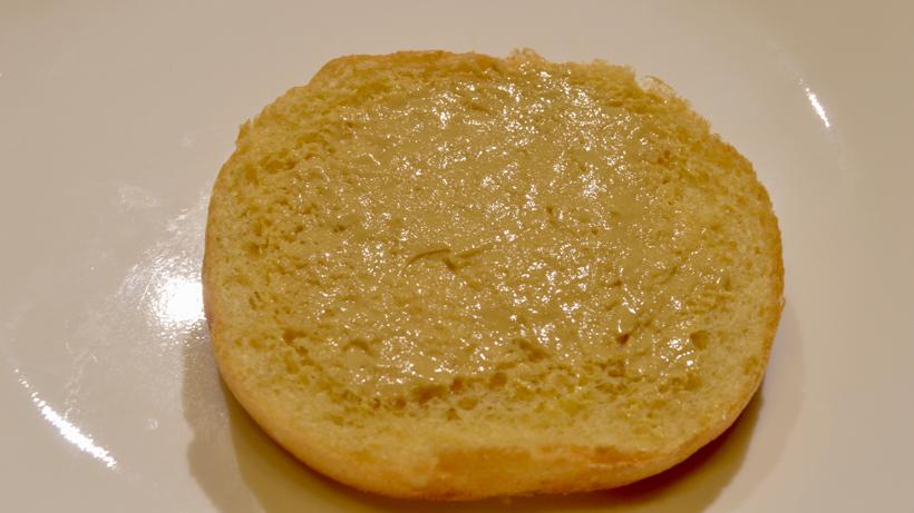Spreading dijon mustard on burger bun