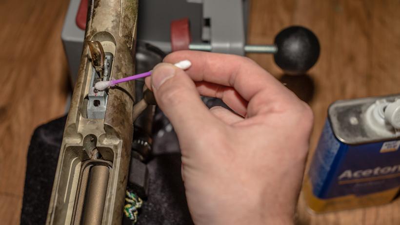 Applying acetone to clean rifle trigger adjustment screw
