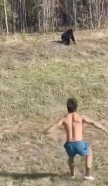 Shirtless man chasing black bear